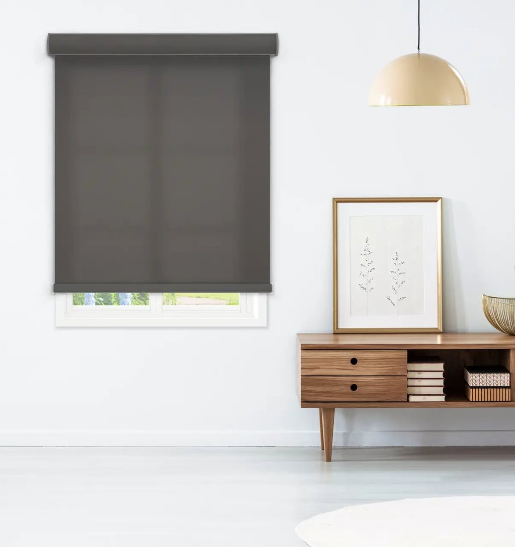 Dark gray roller shade in a modern living room setting beside a mid-century wood console table with books and framed art