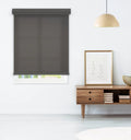 Dark gray roller shade in a modern living room setting beside a mid-century wood console table with books and framed art